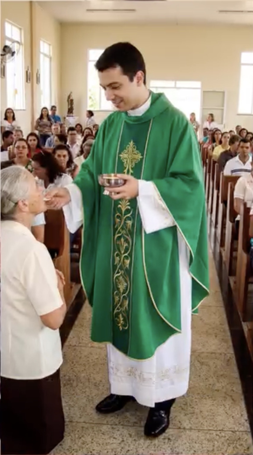 Padre Miguel antes da amputação, em pé, dando a comunhão